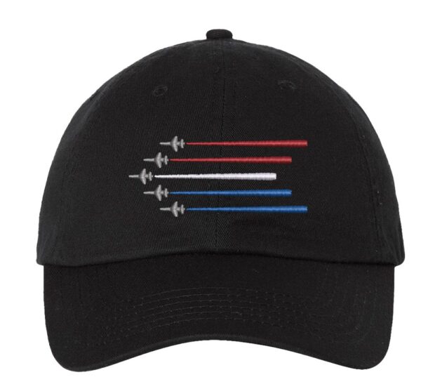 Image shows a baseball cap with embroidered Air Force airplanes and Navy aircrafts design, against a backdrop of red, white, and blue trails in the sky.