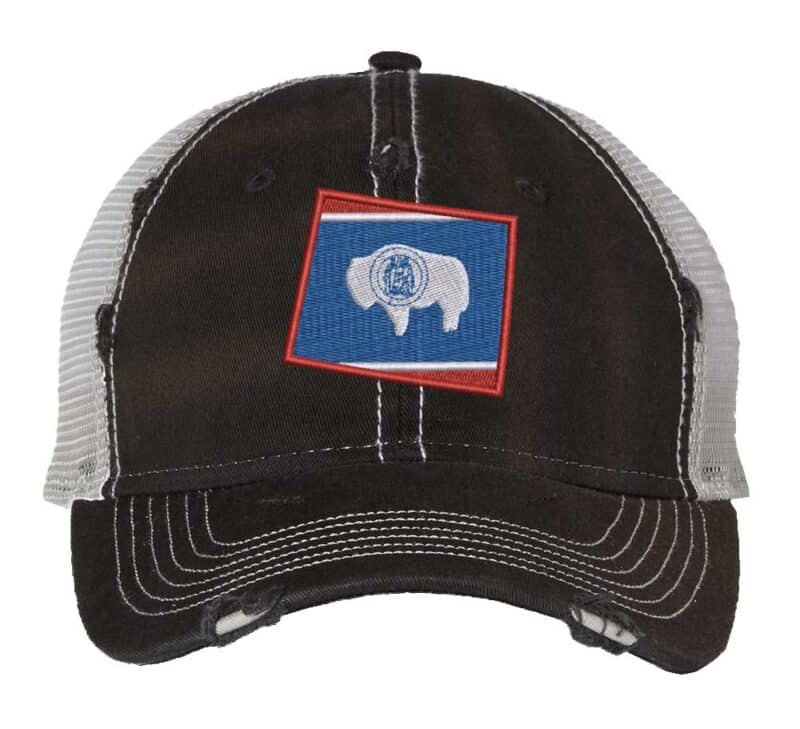 Distressed Wyoming trucker hat with embroidered state flag design, mesh back, and adjustable strapback closure.