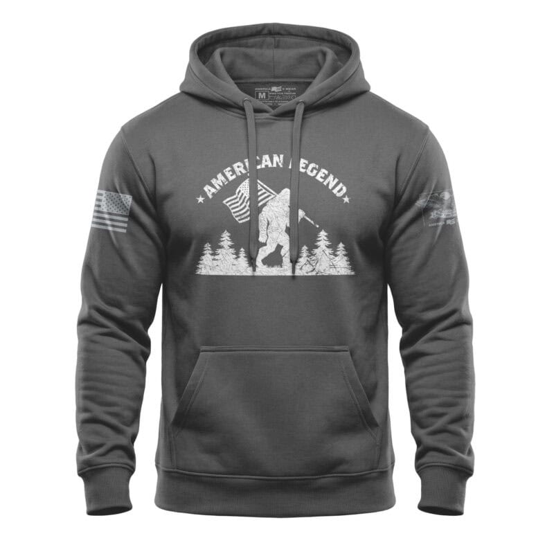 Hoodie featuring Bigfoot silhouette with patriotic flags and trees, perfect for outdoor enthusiasts.