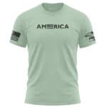 Light green American flag T-shirt with USA flag patch on sleeve and "AMERICA" text on chest.
