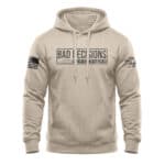 Beige hoodie with "Bad Decisions" graphic, American flag patch, and logo on sleeve.