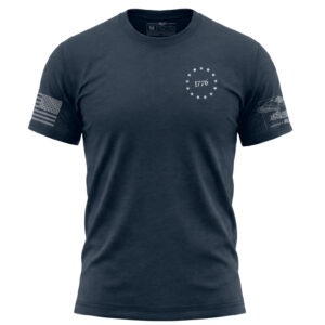 Navy blue T-shirt with "1776" and stars emblem, American flag patch on sleeve, patriotic design.