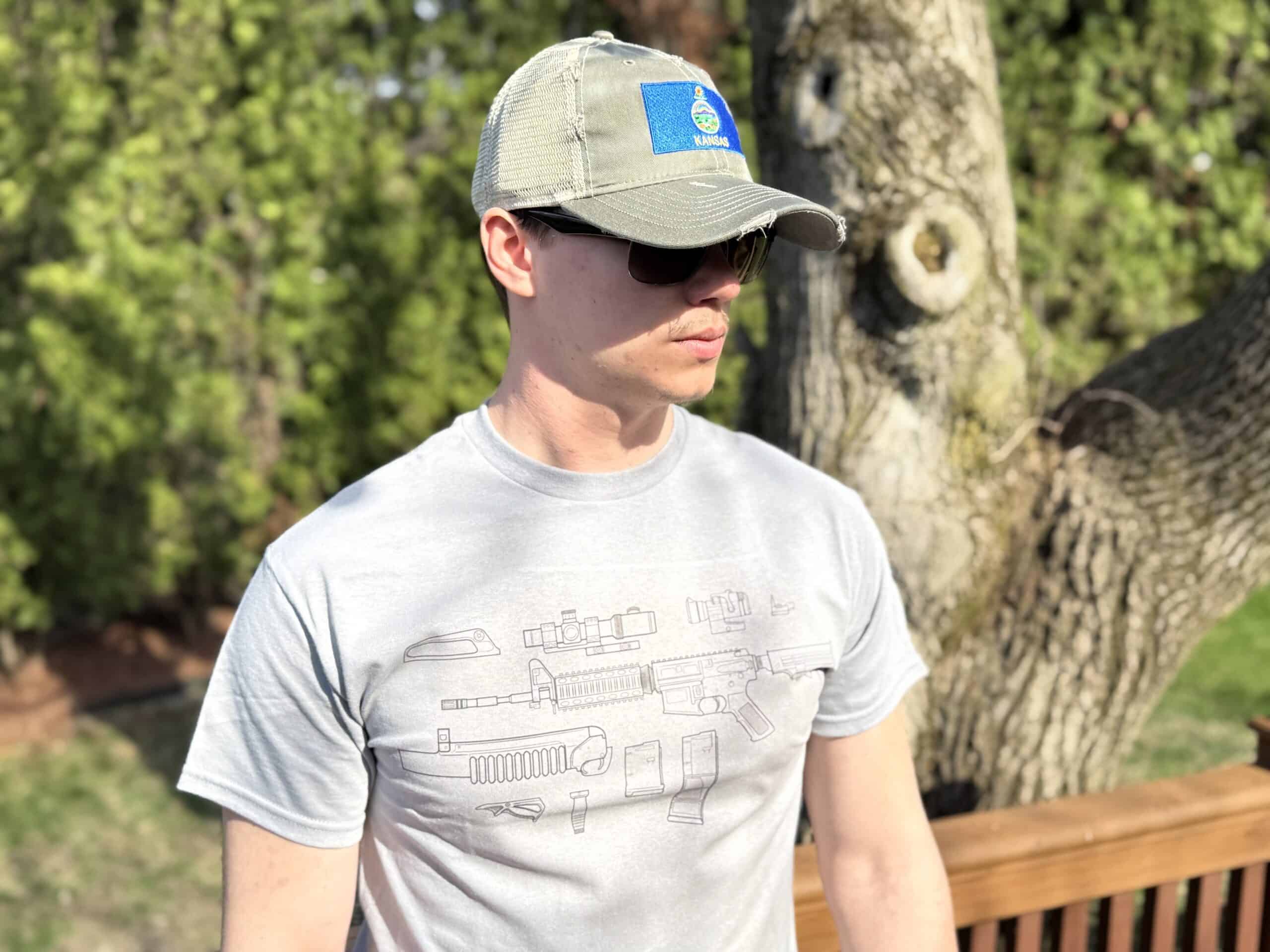 Young man wearing patriotic-themed t-shirt and cap outdoors.