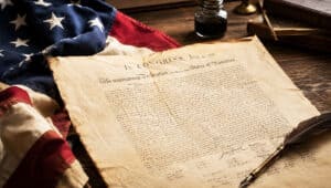 Historical Declaration of Independence with American flag and quill pen.