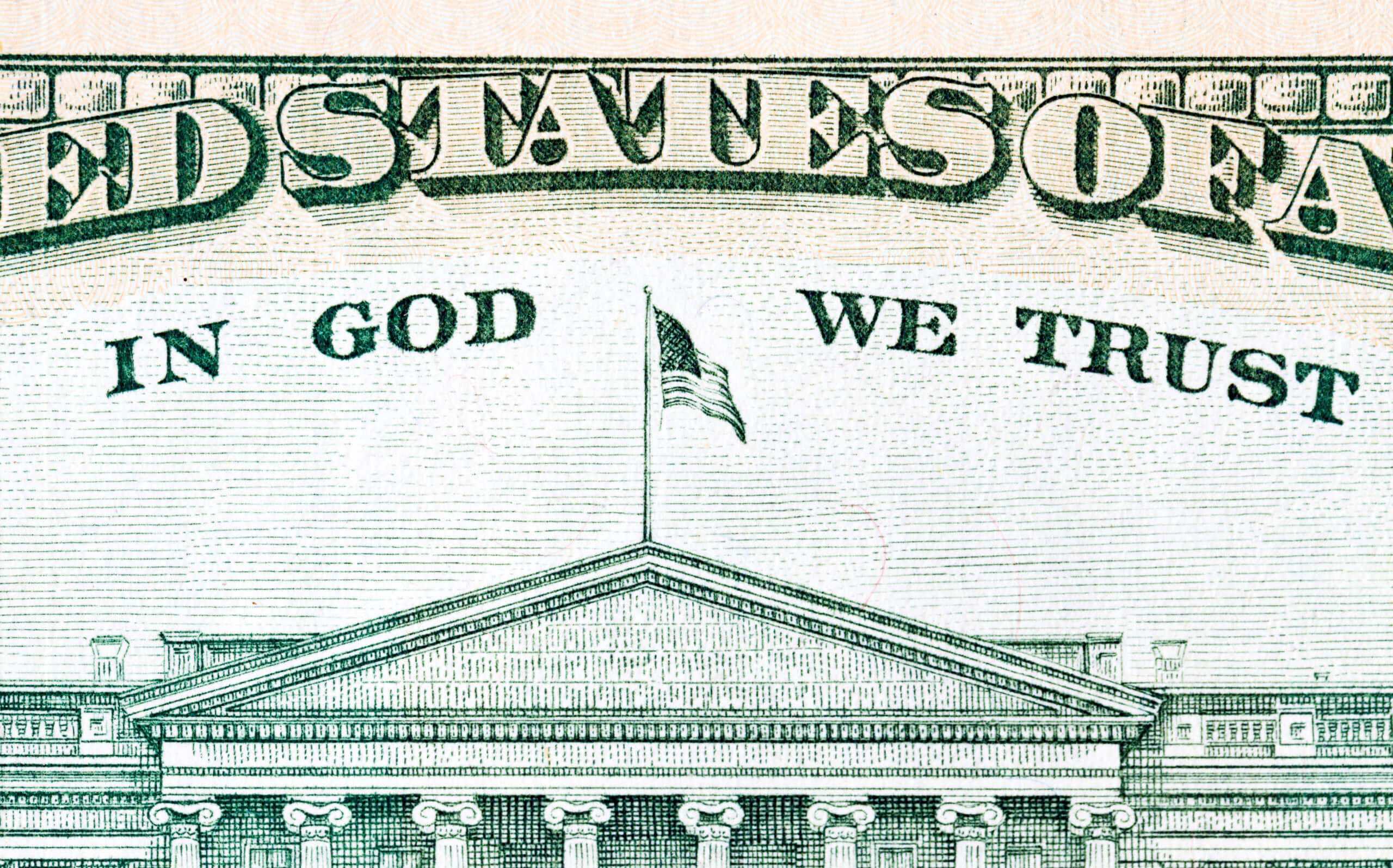 Close-up of the US Capitol building with 'In God We Trust' on dollar bill.