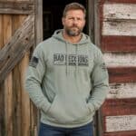 Man wearing a distressed hoodie with 'Bad Decisions' print outdoors.