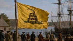 Historic-style yellow Gadsden flag with a coiled rattlesnake displayed in a Revolutionary-era American setting.