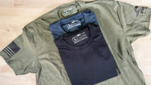 Olive and navy US-made t-shirts stacked on an olive green shirt.